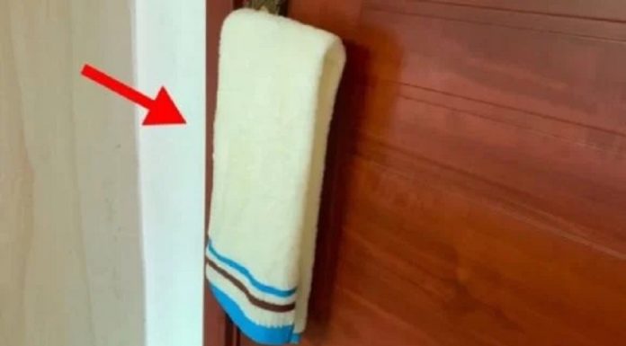 Why should you hang a wet towel on the door handle in a hotel?