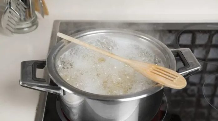What is the purpose of placing a wooden spoon over a boiling pot?